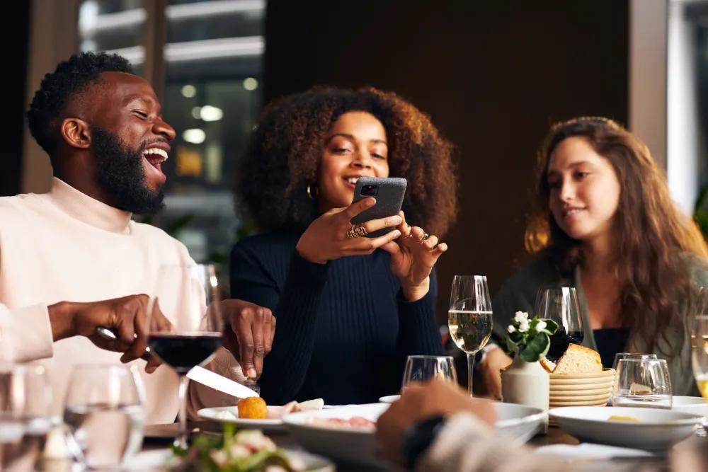 Una donna in un ristorante paga comodamente il conto con un codice QR con il suo smartphone.