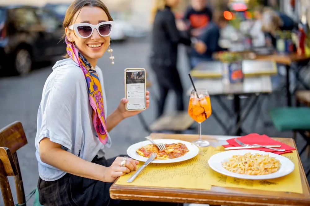 Dans un restaurant, une femme règle commodément sa note à l'aide d'un code QR et de son smartphone.